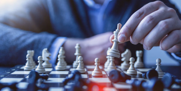 Person playing chess with white pieces, holding the queen piece.