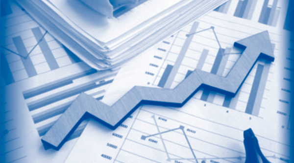 Wooden arrow on top of piles of papers with different graphs illustrated