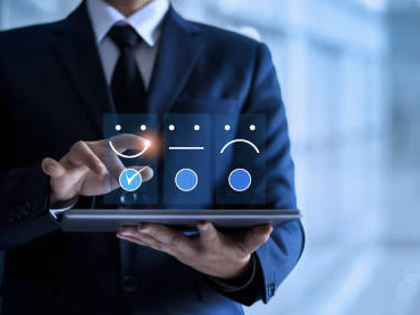 Man in a suit holding an ipad with three floating emoji options above it, selecting the similing face