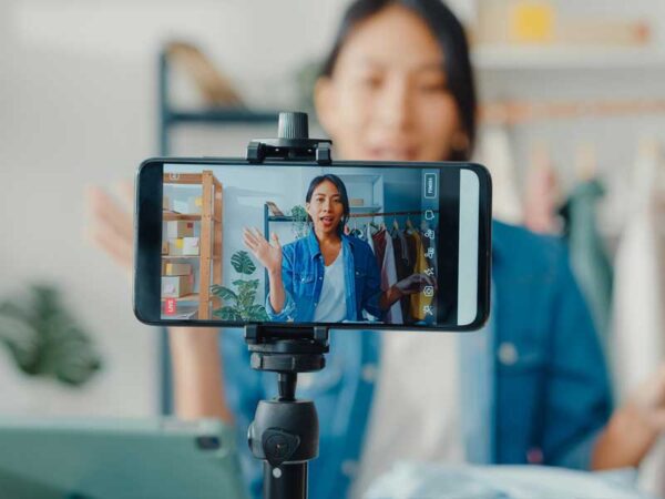Woman sitting and speaking as a phone records her video