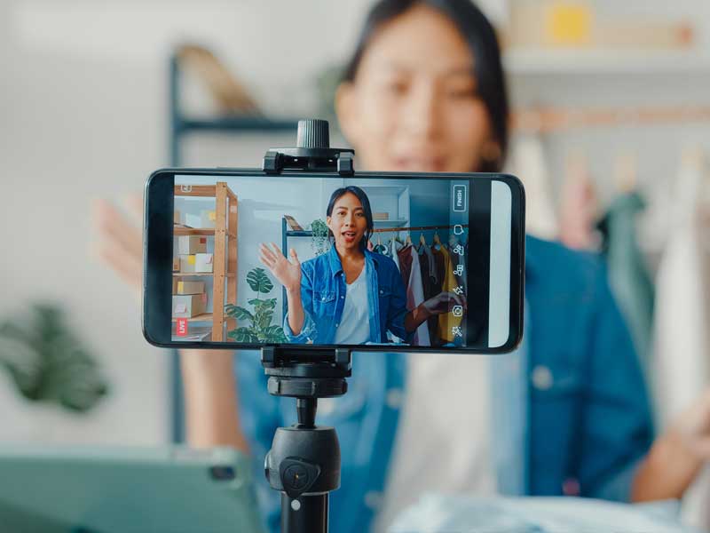 creator-economy-businesses Woman sitting and speaking as a phone records her video