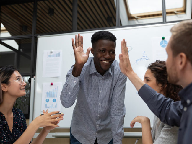 reputationships Man high-fiving a teammate at a business meeting with four people