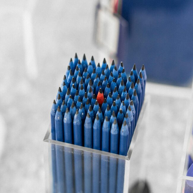 B2B Brand Differentiation One different red pencil amongst blue pencils.